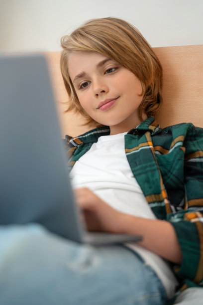 聪明的白人中学男孩使用笔记本电脑。孩子在键盘上打字。玩电子游戏。在线导师数字课堂，在家电脑上进行网络教学。虚拟教育。电子教育。垂直图片下载