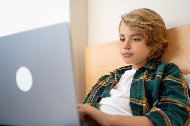 聪明的白人中学男孩使用笔记本电脑。孩子在键盘上打字。玩电子游戏。在线导师数字课堂，在家电脑上进行网络教学。虚拟教育。电子教育。图片下载