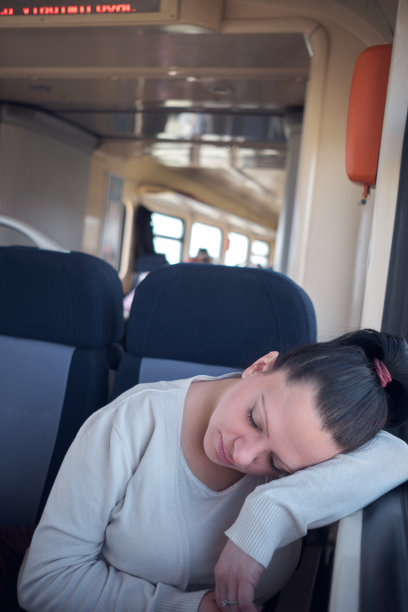 一名女子在旅行时睡在火车座位上。图片下载