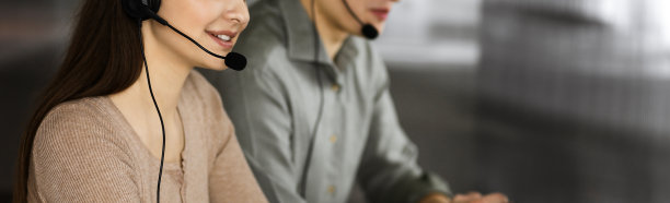 两名戴着耳机的年轻人坐在办公室的办公桌前与客户交谈。关注女性。呼叫中心接线员在工作图片下载