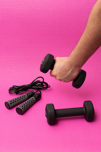 一个人举哑铃在粉红色的背景垂直视图。图片下载