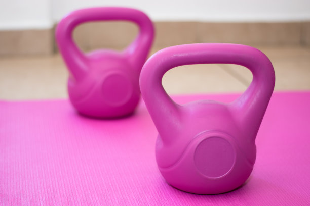 粉色垫子上放着两个粉色壶铃图片下载