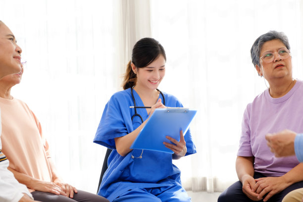 护理治疗师与一群亚洲老年人围成一圈坐在一起，检查他们的身心健康状况。养老院为互助小组提供了便利图片下载