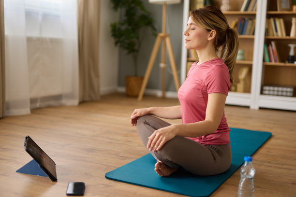 年轻女子在家里做瑜伽和冥想，同时在数字平板电脑上观看教程图片下载