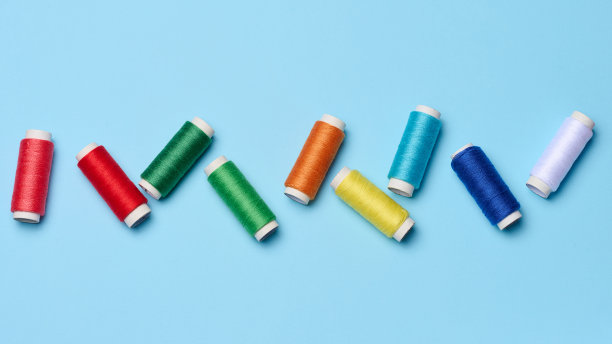 蓝色背景上的彩色缝纫线线轴，俯视图图片下载