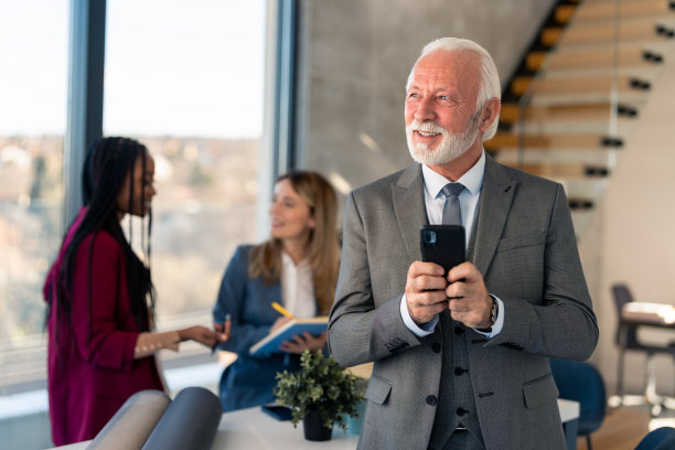西装革履的老年商人拿着智能手机，无忧无虑图片下载