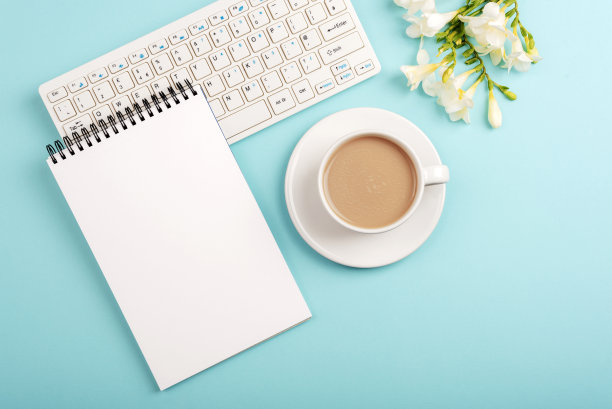 电脑键盘，空白记事本和咖啡杯放在蓝色的小苍兰花桌上。俯视图，平面布局，模型图片下载