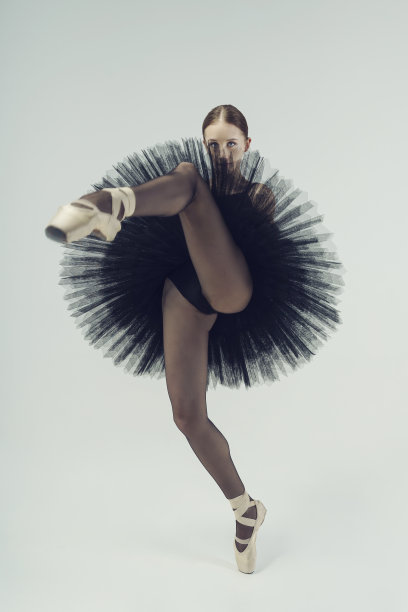 身着黑色芭蕾舞裙的芭蕾舞女演员在动作中展示芭蕾舞的元素图片下载