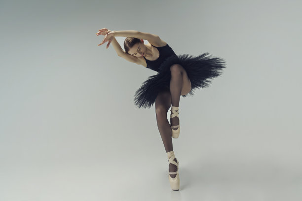 身着黑色芭蕾舞裙的芭蕾舞女演员在动作中展示芭蕾舞的元素图片下载
