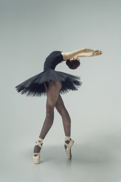 身着黑色芭蕾舞裙的芭蕾舞女演员在动作中展示芭蕾舞的元素图片下载