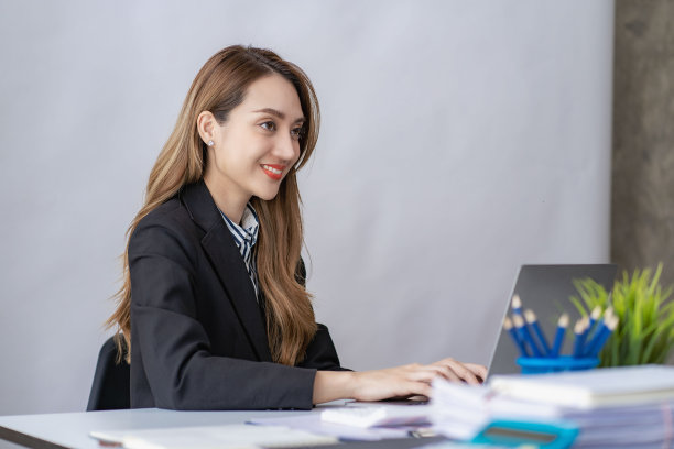 在明亮现代的办公室里，微笑的亚洲女商人在她的办公桌上用平板电脑工作，用图表文件计算财务报告费用图片下载