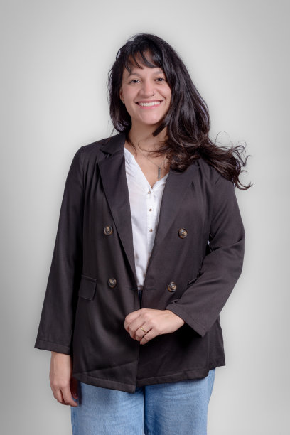 年轻的女商人看着相机在工作室与灰色背景的肖像图片下载