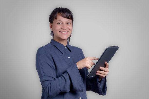 肖像的女商人使用数码平板电脑在工作室对灰色背景图片下载