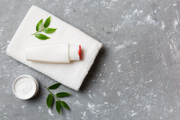 化妆品洗发水瓶子模型和毛巾放在彩色桌子上。浴室背景，卫生间配件，用于手部和身体护理图片下载