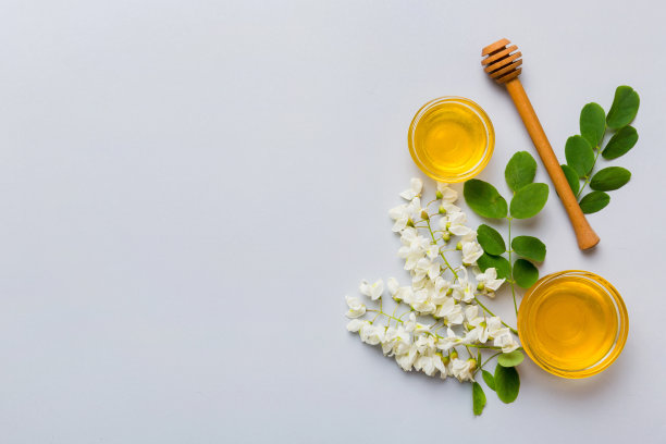 蜂蜜罐与金合欢花和叶子。新鲜蜂蜜顶部视图平铺图片下载