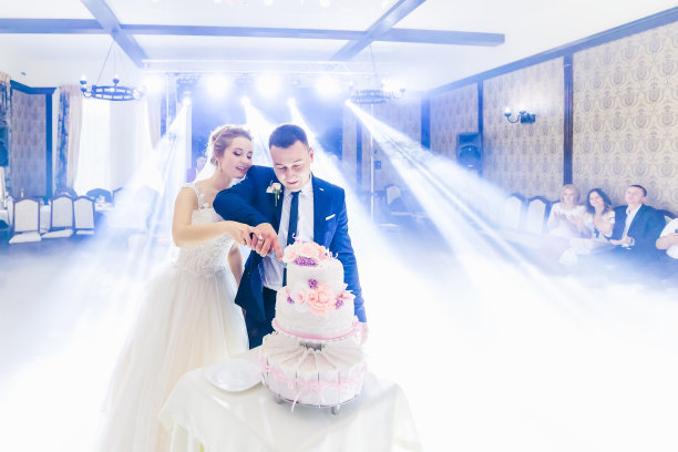 餐厅大厅里的新婚夫妇正在切结婚蛋糕。图片下载