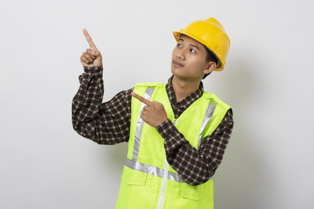 微笑着年轻的亚洲建筑用手指指着白色背景上孤立的侧复制空间。营销和广告概念。图片下载