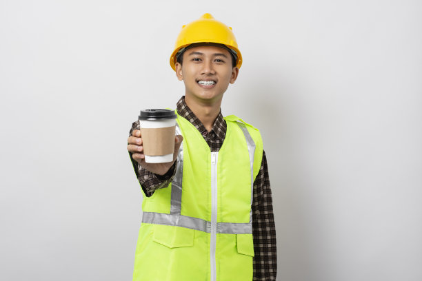 年轻的亚洲建筑工人站在白色背景上给热咖啡杯图片下载