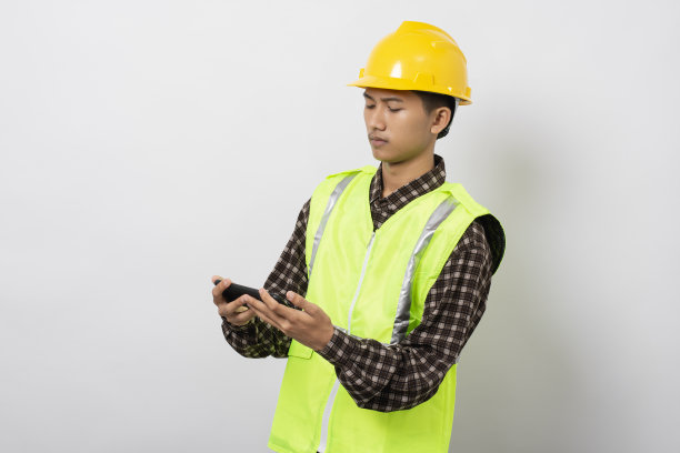 年轻的亚洲建筑工人微笑快乐使用智能手机隔离在白色背景图片下载