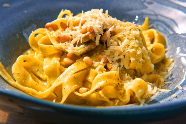 意大利面，坚果，大蒜，橄榄油。侧视图，特写。意大利面加帕尔马干酪。美味的意大利面放在蓝色的陶瓷盘子里。阿弗雷多意面晚餐，奶油白酱。意大利面条。图片下载