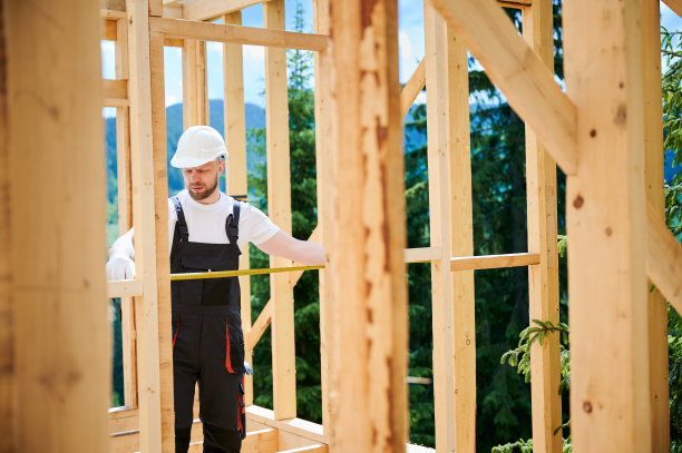 木匠在建造木结构房屋时用卷尺测量距离。图片下载