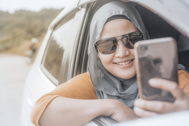 穆斯林女士在车里用智能手机自拍图片下载