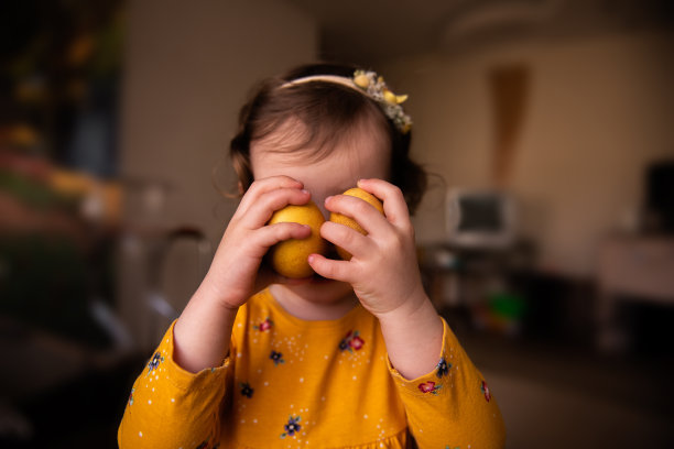 穿着裙子的小女孩拿着两个用天然姜黄颜料画的复活节彩蛋靠近脸。肖像图片下载