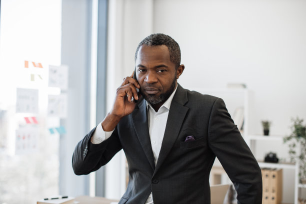 西装革履的男人在办公室用智能手机聊天图片下载