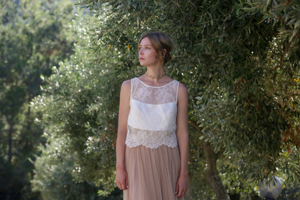 女性的时尚肖像在白色蕾丝上衣与绿色植物后面，暑假时尚图片下载