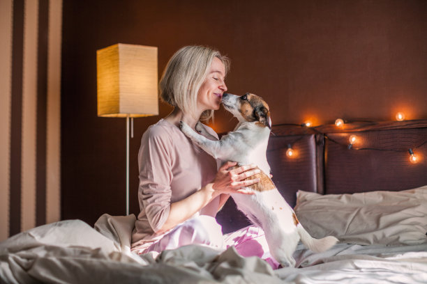 快乐的中年妇女坐在床上伸展双臂图片下载