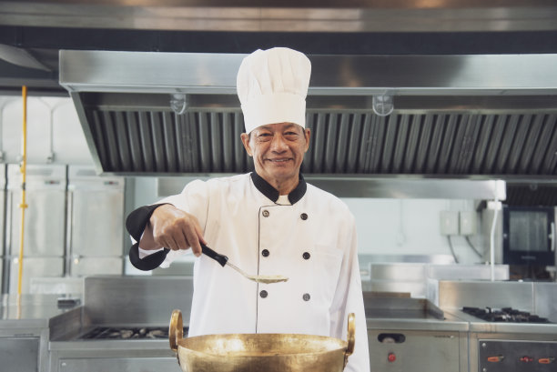 厨师在餐厅厨房的炉子上品尝酱汁图片下载