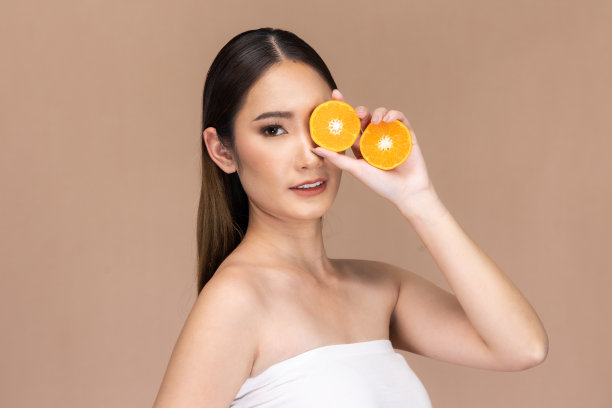 美丽的亚洲女人摆出橙色和积极的情绪，孤立在米色背景上，美容化妆品和水疗面部护理概念。图片下载