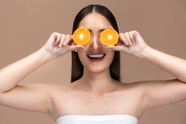 美丽的亚洲女人摆出橙色和积极的情绪，孤立在米色背景上，美容化妆品和水疗面部护理概念。图片下载