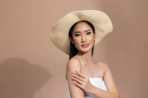 美丽的亚洲女性触摸眉毛微笑，皮肤干净清新，快乐与积极的情绪，隔离在米色背景上，美容化妆品和水疗面部护理概念。图片下载