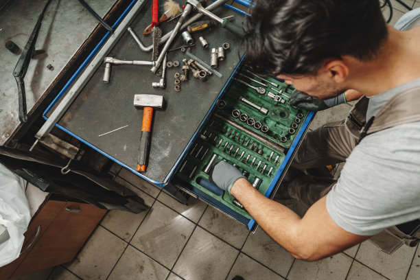 在汽车服务中，男技术员站在工具台附近图片下载