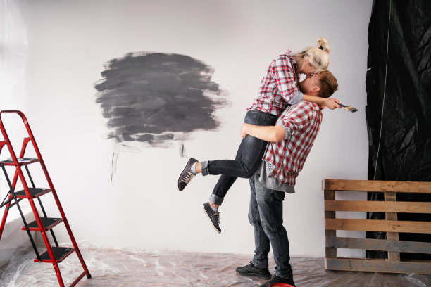 家庭装修房子。一对情侣一边粉刷墙壁，一边亲吻。修复和关系概念图片下载