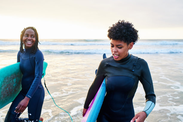 两个冲浪爱好者带着他们的冲浪板从海里出来图片下载