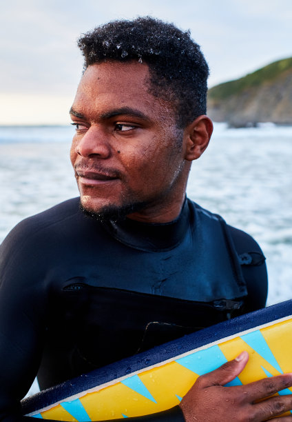 一个年轻人拿着冲浪板的肖像，背景是大海图片下载