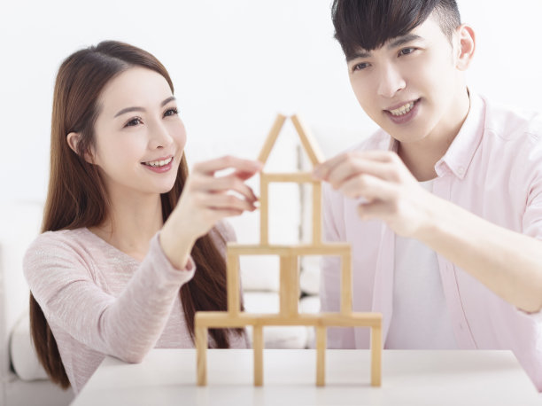 幸福的年轻夫妇用木砖为家的概念建造房子图片下载