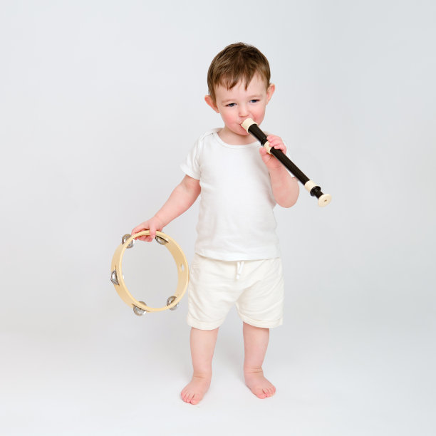 快乐的宝贝玩乐器工作室白色背景。一个微笑的孩子和吹笛子的肖像。孩子2岁左右(1岁9个月)图片下载