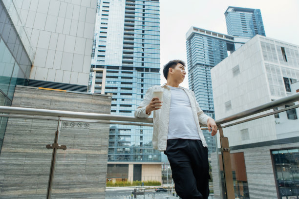 一名男性商人在公司外的阳台上休息，喝着咖啡——促进健康，平衡工作和生活图片下载