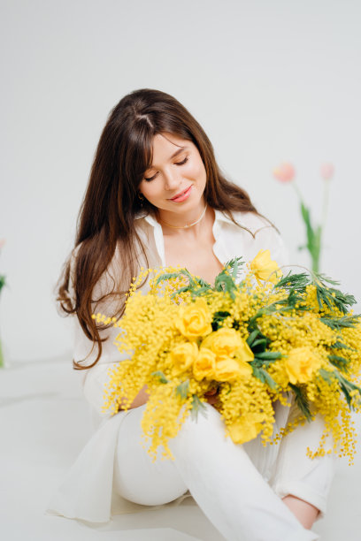 美丽温柔的女人黑发与一束黄色郁金香和含羞草图片下载