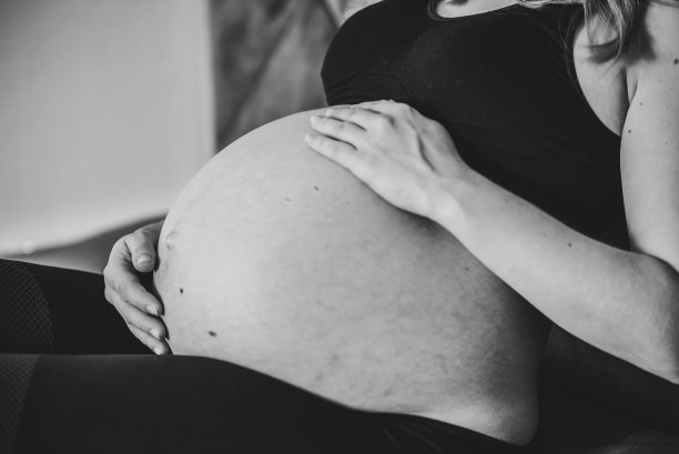 怀孕的女人。黑白照片。怀孕，母性，生育概念。女人的腹部特写。雌性等待新生婴儿。怀孕的女孩抚摸，抱着肚子，关心健康。图片下载