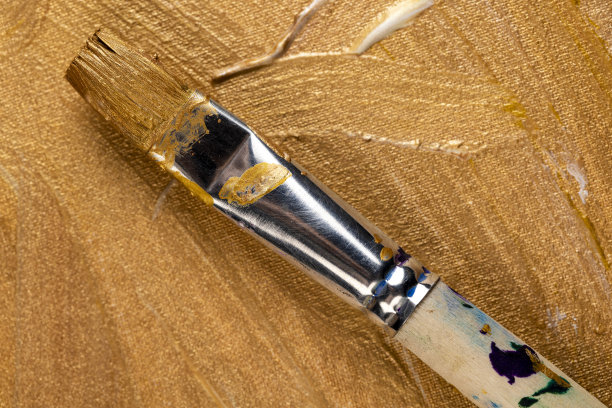 用艺术画笔在画布上用金色颜料作画图片下载