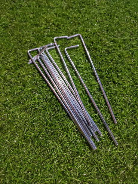 一堆金属做的帐篷挂钩散落在绿草地上图片下载