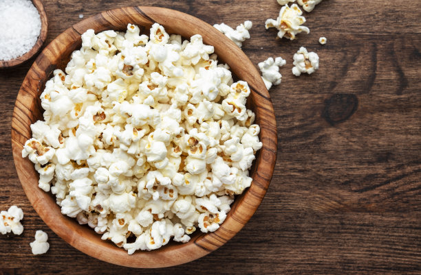 木碗里的咸爆米花，不健康的食物，木制厨房桌子背景，俯视图图片下载