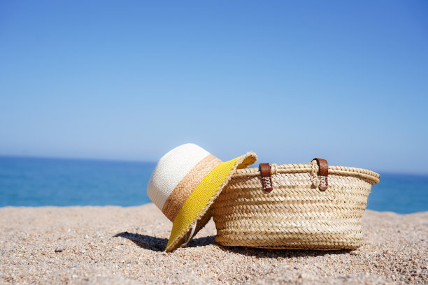 一顶帽子和一个袋子在沙滩上的沙子上复制天空的空间。暑假图片下载