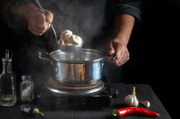 专业厨师在餐厅厨房用平底锅煮肉馅饺子。厨师工作时的手特写。免费广告位。图片下载