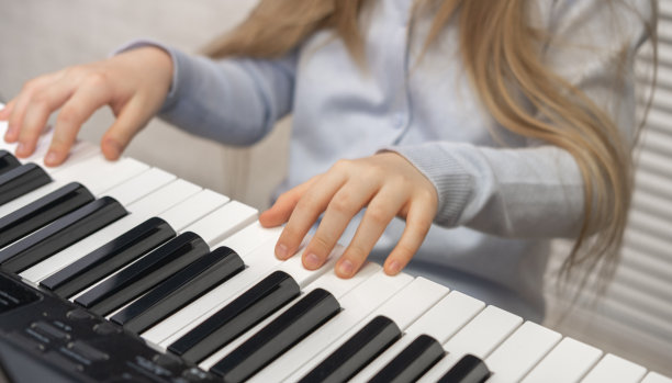 女孩在弹钢琴。前视图。选择性地关注孩子的手指。音乐教育，课。从上面。图片下载