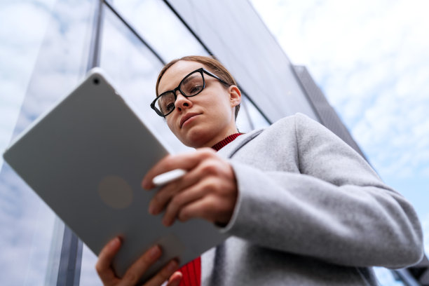 自信的女人戴着眼镜在平板电脑上工作。图片下载